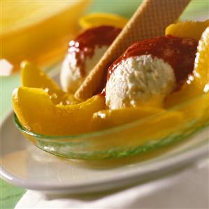 Peach Melba with raspberry sauce and wafer in a glass dish