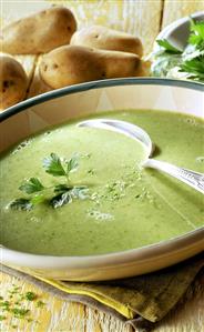 Ramsons (wild garlic) soup in soup plate, potatoes behind