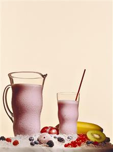 Ice-cooled berry shake in glass and jug