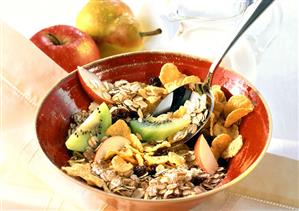 Muesli with fruit in a red bowl; milk jug