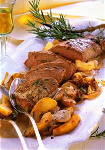 Pork fillet with apples, onions and rosemary on platter