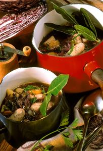 Red cabbage soup with sausages and bay leaf in pots