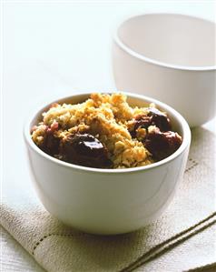 Plum crumble in white bowl