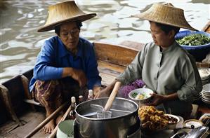 Thai women cooking soup on a boat