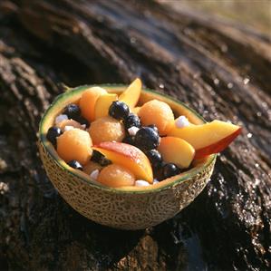 Fruit salad in a melon half on a rock