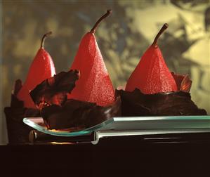 Three poached pears in red wine in chocolate coating