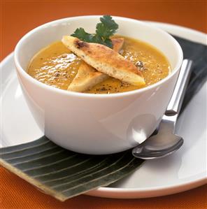 Pumpkin soup with focaccia bread in a white bowl