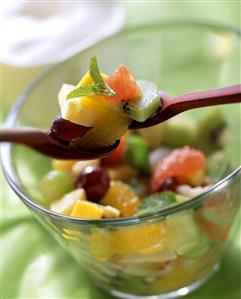 Exotic fruit salad in glass dish and on wooden spoons (1)