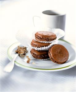 Chocolate macaroons in paper cases on plate; coffee