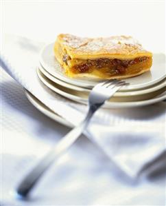 A piece of apple cake with raisins on pile of plates