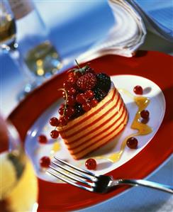 Small layered cake with summer berries on plate