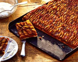 Plum cake on baking sheet and plate; cream