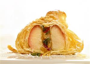 Apple in puff pastry being sprinkled with icing sugar