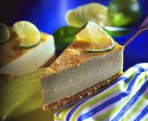 A piece of caipirinha cheesecake with limes on cake slice