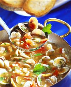 Mussel soup with barley on ladle and in soup pot