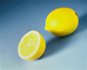 Whole and half lemon on blue background