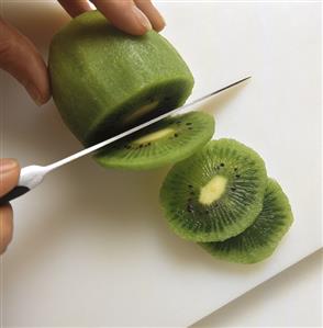 Slicing peeled kiwi fruit