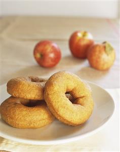 Apple doughnuts on plate in front of fresh apples