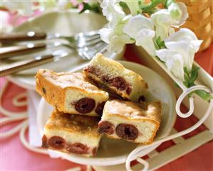 Pieces of cherry cake on white plate; white flowers