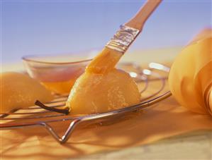 Spreading apricot jam on poached pear