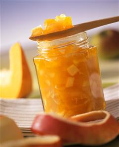 Apple and pumpkin preserve in jar and on wooden spoon