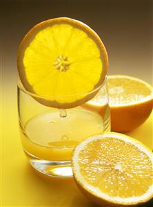 Orange juice in glass with slice of orange; orange halves