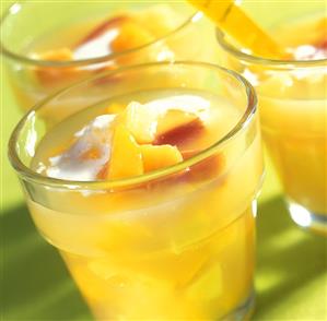 Yellow fruit compote with cream in glasses for summer party