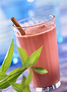 Cherry whey cocktail with cinnamon stick; green leaves