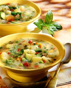 Minestrone with basil in yellow soup plates