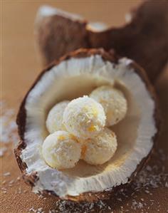 Coconut chocolates with grated coconut in half a coconut