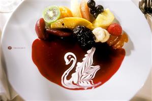 Fruit with red sauce, decorated with cream swan