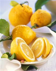 Fresh lemons with leaves in ceramic bowl