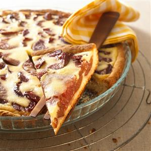 Plum tart, a piece cut, in glass baking dish