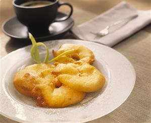 Apple fritters with sugar; cup of coffee