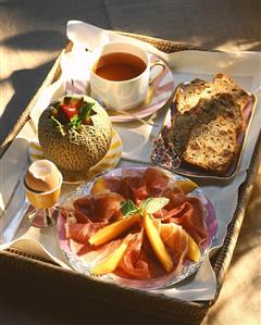 Breakfast Tray with Prosciutto, Melon, Soft Boiled Egg, Bread and Tea