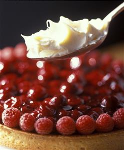 A raspberry and cherry tart with cream on spoon