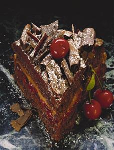 A piece of chocolate and cherry gateau with chocolate curls