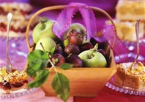 Pieces of apple cake and plum cake, fruit basket between them