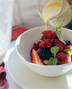 Pouring custard over berry salad