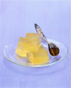 Three cubes of apple jelly on glass plate with spoon