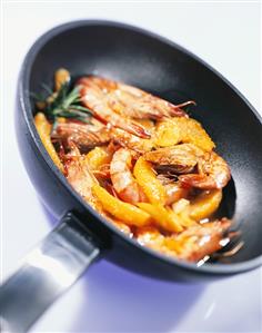 Gambas in frying pan in orange sauce