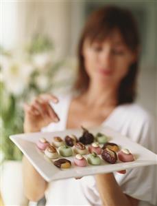 Woman reaching for chocolates on plate