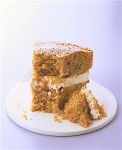 Piece of orange carrot cake with icing sugar, a bite taken