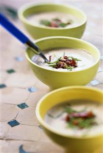 Three bowls of chestnut soup with bacon and chives