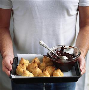 Man serving profiteroles with chocolate sauce