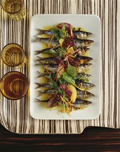 Sardines with oranges on white platter