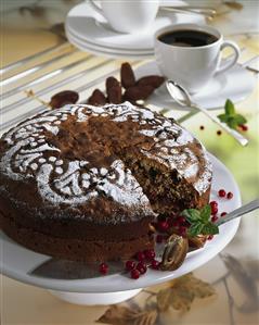 Date cake, a slice taken, cup of coffee in background