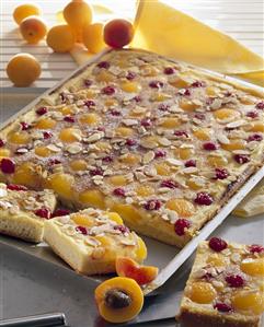 Apricot and cherry cake with flaked almonds on baking tray