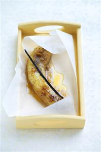 Banana with vanilla pod and honey sauce in parchment paper