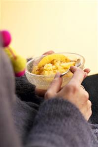 Hands holding a glass dish of apple puree in wine sauce